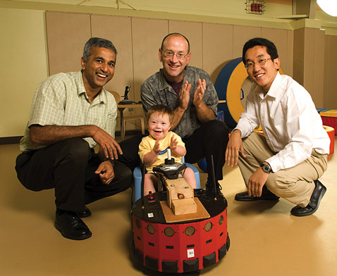 Один из отстающих в развитии малышей с разработчиками UD1 в помещении центра раннего развития. Слева направо: Сунил Агравал, Джеймс Галловей и докторант факультета машиностроения Цзи Чуль-Жу (Ji-Chul Ryu).
