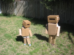 дети примеряют костюм робота из картона на себе